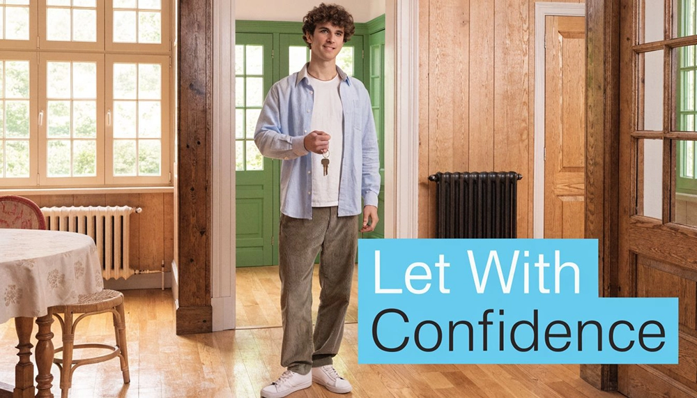 A young man holding a set of house keys stands in the doorway of a bright home.