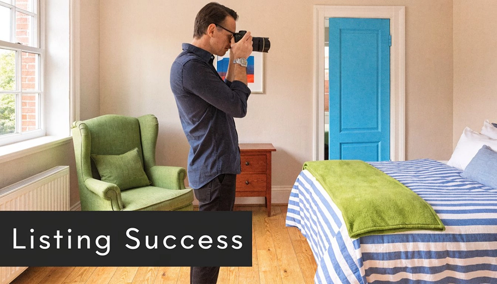 A professional photographer taking photos of a stylish spare bedroom for a real estate listing